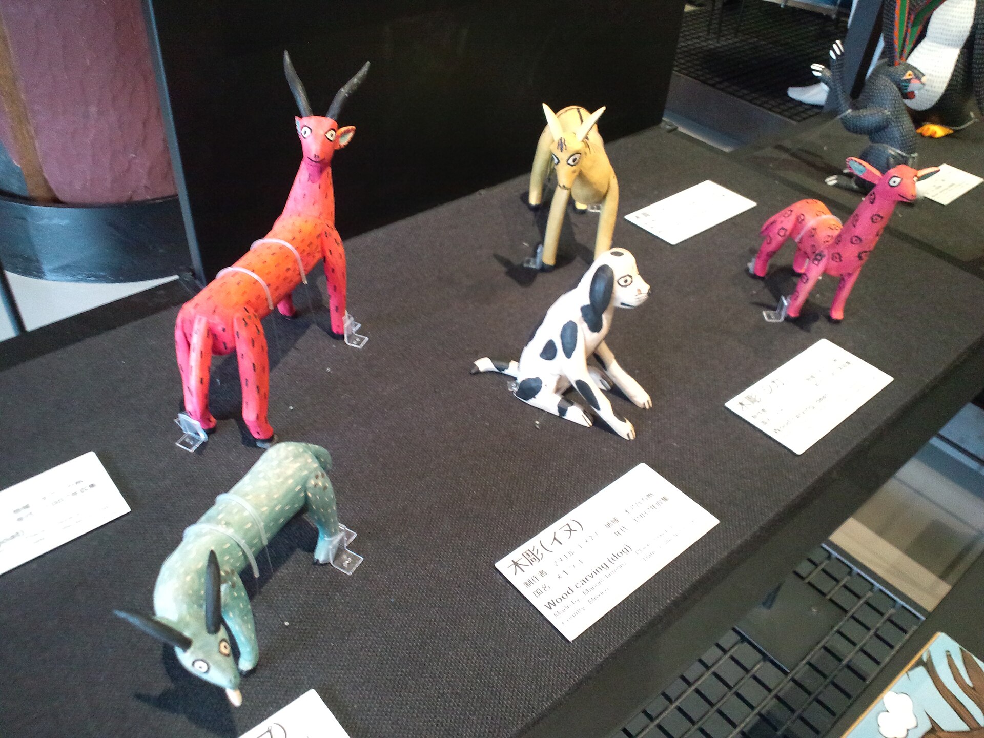Alebrijes de madera pintados, de animales de patas largas y cuerpo de colores, exhibidos sobre una mesa negra